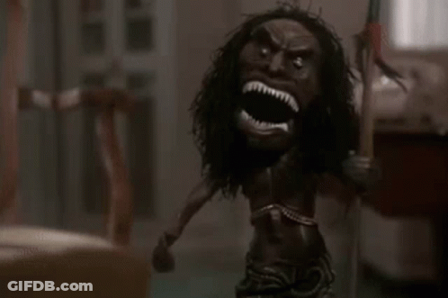 A Doll With A Long Haired Head Is Holding A Spear In A Room . GIF