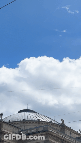 A Dome Shaped Building With A Blue Sky And Clouds Behind It GIF