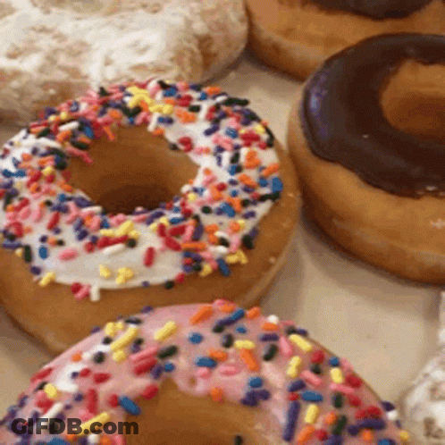 A Donut With Pink Frosting And Sprinkles On Top GIF
