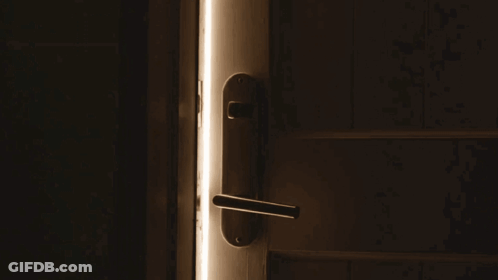 A Door Is Open To A Dark Room With A Light Shining Through It GIF