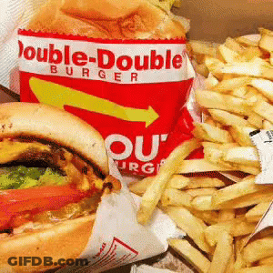 A Double-Double Burger And French Fries Are Sitting On A Table GIF