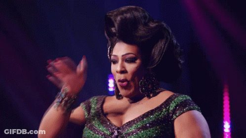A Drag Queen In A Green And Black Dress Is Making A Funny Face GIF