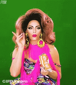 A Drag Queen In A Pink Dress Is Holding A Bag Of Chips And Making A Funny Face . GIF