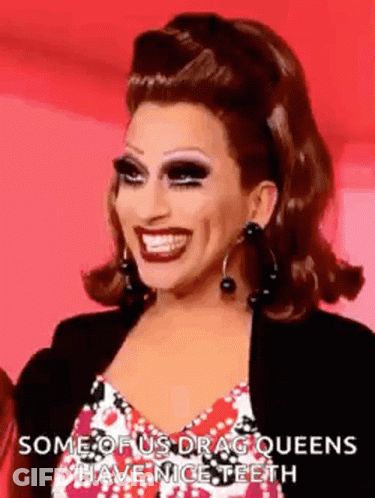 A Drag Queen Is Smiling And Wearing Earrings . GIF
