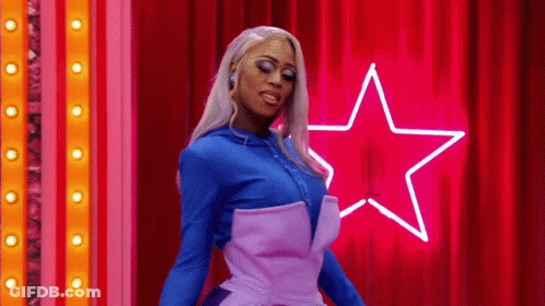 Drag Queen In Front Of Red Curtain And Neon Star GIF