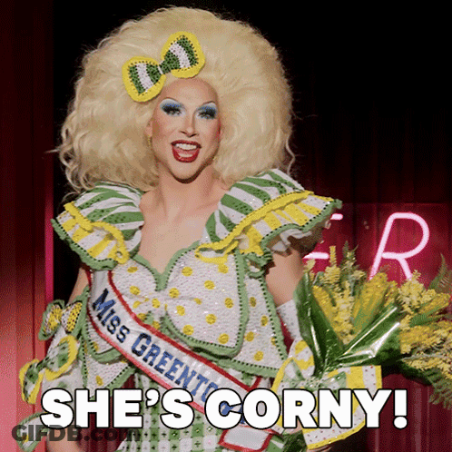 A Drag Queen Is Wearing A Miss Greenton Sash And Holding A Bouquet Of Yellow Flowers GIF