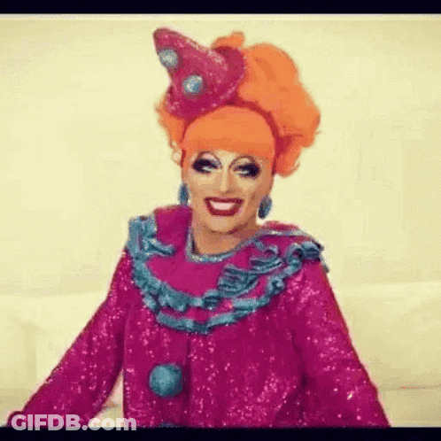 A Drag Queen Is Wearing A Pink And Blue Clown Costume . GIF