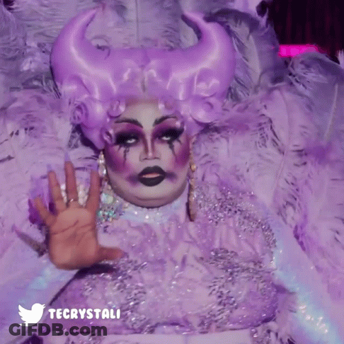 A Drag Queen Is Wearing A Purple Feathered Costume And A Twitter Logo GIF