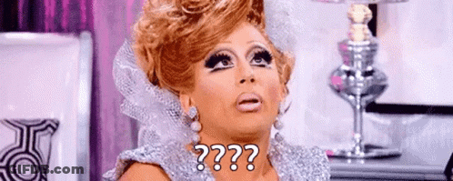 A Drag Queen Is Wearing A Silver Dress And Earrings And Making A Funny Face . GIF
