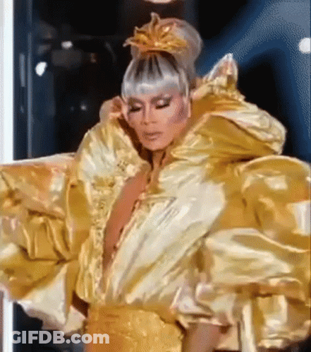 A Drag Queen Is Wearing A Very Large Gold Dress And A Crown On Her Head . GIF