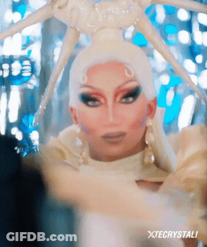 Drag Queen In White Costume With Spider Headpiece GIF