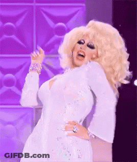 A Drag Queen Is Wearing A White Dress And Dancing On A Stage . GIF