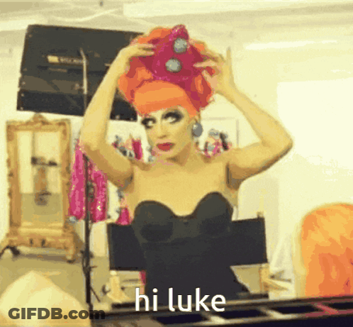 A Drag Queen Says Hi Luke While Putting On A Crown GIF