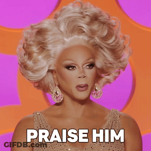A Drag Queen Says Praise Him In Front Of A Pink Background GIF