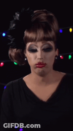 A Drag Queen Wearing A Black Dress And A Black Feather In Her Hair GIF