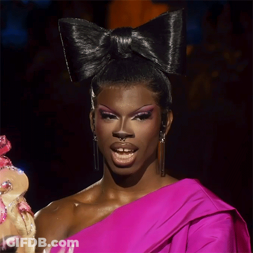 A Drag Queen Wearing A Pink Dress And A Large Black Bow In Her Hair GIF