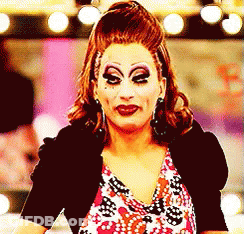 A Drag Queen Wearing Makeup And A Black Jacket GIF