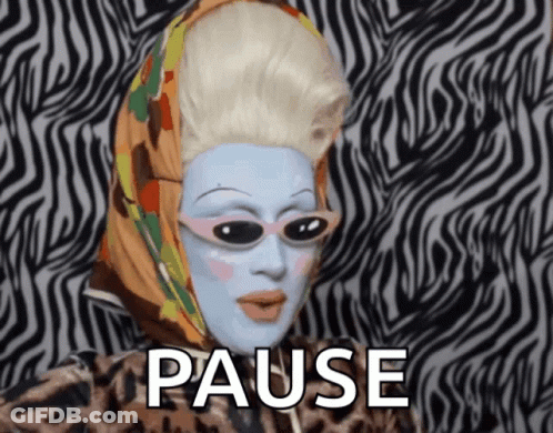 A Drag Queen With A Scarf Around Her Head And The Word Pause Behind Her GIF