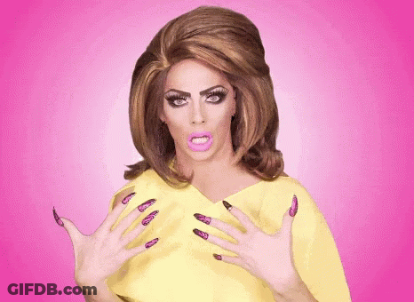 A Drag Queen With Long Purple Nails And A Yellow Top GIF