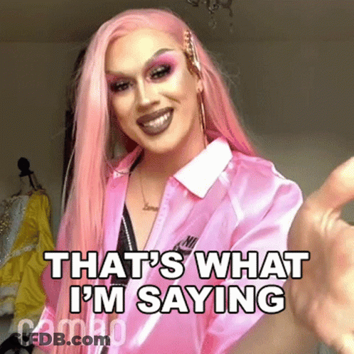 A Drag Queen With Pink Hair Is Wearing A Pink Shirt And Giving A Thumbs Up Sign . GIF