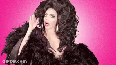 A Drag Queen With Very Long Hair Is Wearing A Black Fur Coat And Feathers . GIF