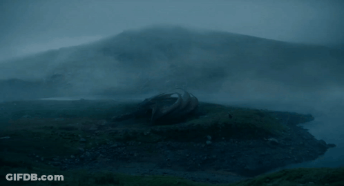 A Dragon Is Laying On The Ground In A Foggy Landscape GIF