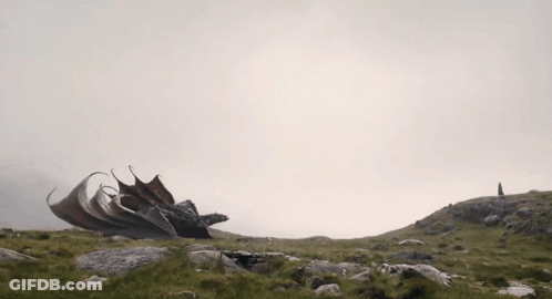 A Dragon Is Sitting On Top Of A Hill With Its Wings Spread GIF