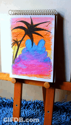 A Drawing Of A Sunset With Palm Trees Is On A Wooden Easel GIF