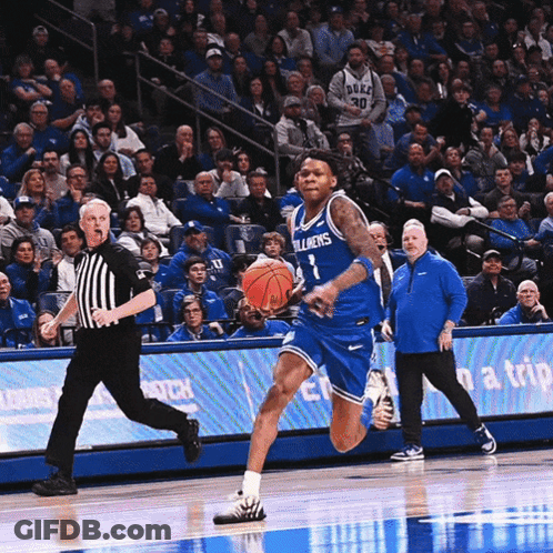 A Duke Basketball Player Dribbles The Ball While A Referee Watches GIF