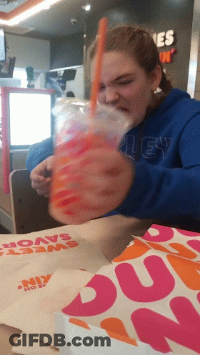 A Dunkin Donuts Bag Sits On The Table Next To A Girl GIF