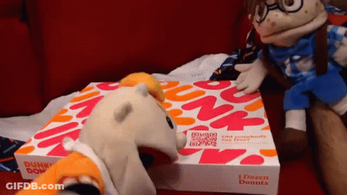 A Dunkin Donuts Box Sits On A Couch Next To Stuffed Animals GIF