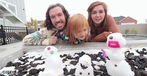 A Family Is Posing For A Picture In Front Of A Pile Of Snowmen GIF