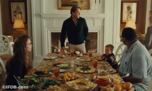 A Family Is Sitting Around A Table With Plates Of Food And Drinks . GIF
