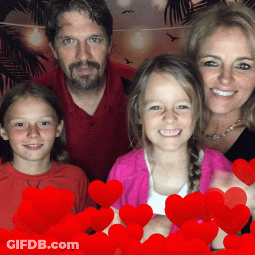 A Family Posing For A Picture With Red Hearts Behind Them GIF