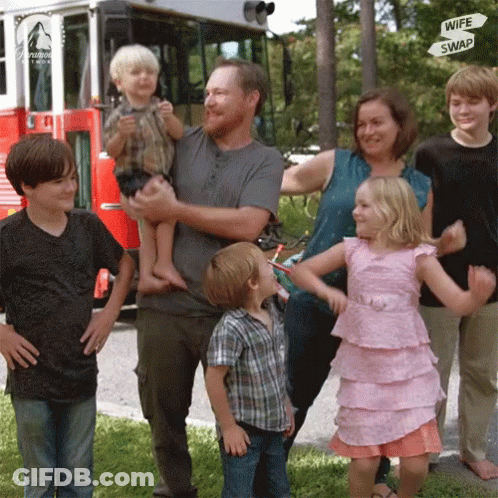 A Family Standing In Front Of A Red Fire Truck With A Sign That Says Wife Swap GIF