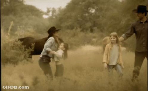 A Family Walking In A Field With A Horse GIF