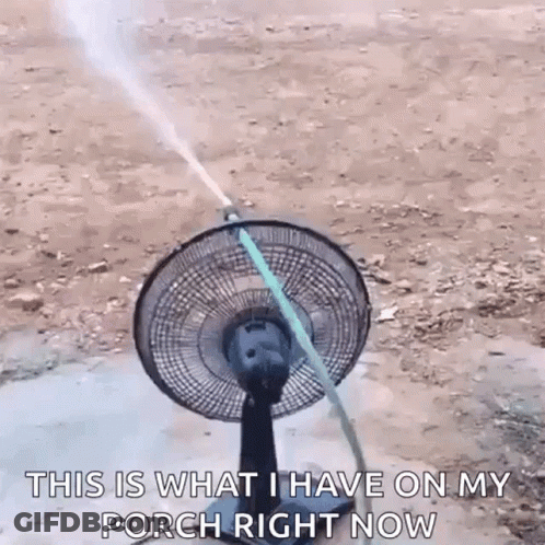 A Fan With A Hose Attached To It Is Being Sprayed With Water . GIF