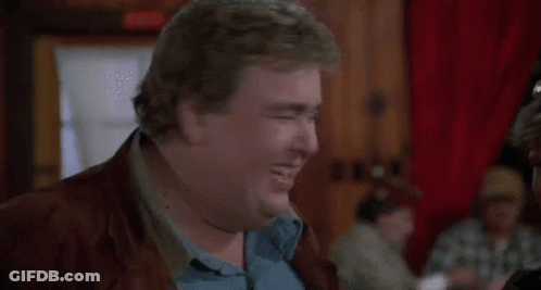 A Fat Man In A Blue Shirt And Brown Jacket Is Making A Funny Face . GIF