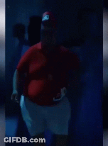 A Fat Man Is Dancing In A Dark Room . GIF