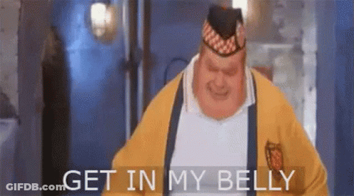 A Fat Man Wearing A Yellow Sweater And A Hat Is Standing In A Room And Saying `` Get In My Belly '' . GIF
