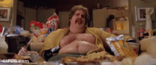A Fat Man With A Mustache Is Sitting On A Couch Eating Chips . GIF