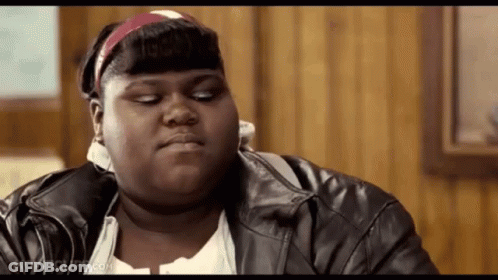 A Fat Woman Wearing A Leather Jacket And A Headband Is Sitting At A Table . GIF