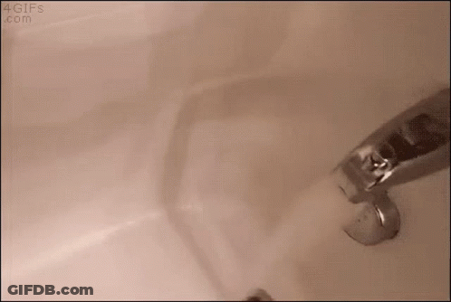 A Faucet Is Turned On In A Bathroom Sink And Water Is Coming Out Of It . GIF