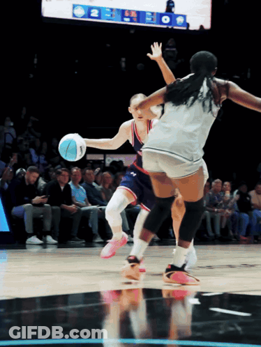 A Female Basketball Player Dribbles The Ball While Another Player Tries To Block Her GIF