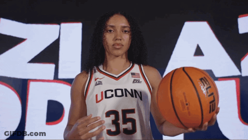 A Female Basketball Player From Uconn Is Holding An Orange Ball GIF