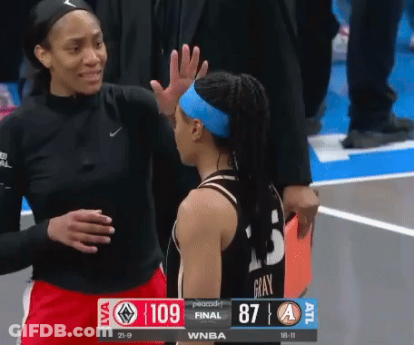 A Female Basketball Player High Fives Another Female Basketball Player During A Game GIF