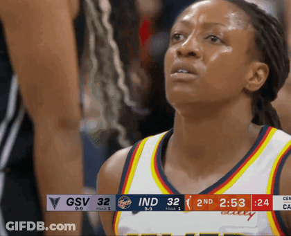 A Female Basketball Player Stands In Front Of A Scoreboard That Says Gsv 32 Ind 32 GIF