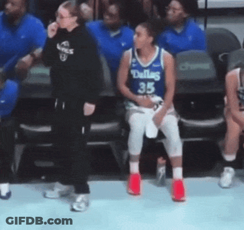A Female Basketball Player Wearing A Dallas Jersey Is Sitting In The Stands . GIF