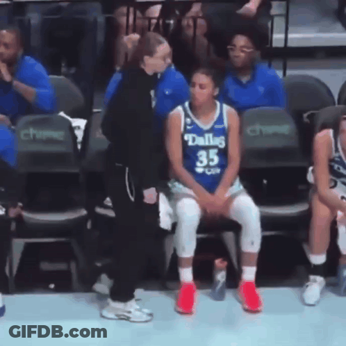 A Female Basketball Player Wearing A Dallas Jersey Sits In The Stands GIF