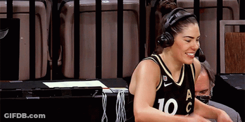 A Female Basketball Player Wearing Headphones And A Number 10 Jersey Is Sitting At A Table . GIF